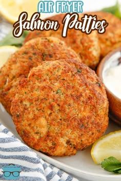 salmon patties on a plate with lemon wedges and ranch dressing in the background