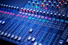 the sound mixing console has many knobs on it's sides and is lit up with colorful lights