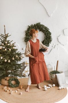 a woman standing in front of a christmas tree wearing an orange dress and holding a book