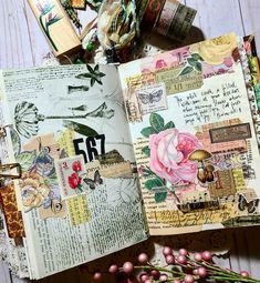 an open book with flowers on it and some other items surrounding it in the background