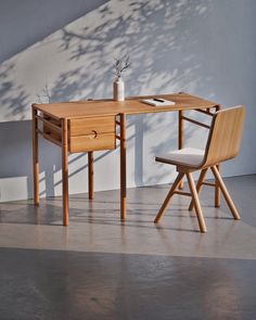 a wooden desk with two chairs next to it and a potted plant on top