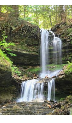 a small waterfall in the middle of a forest