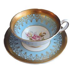 two tea cups and saucers sitting on top of each other with gold trimmings