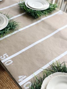 the table is set with plates and napkins on it, along with green grass