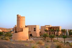 an old building in the desert with palm trees