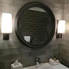 a bathroom sink with a mirror above it and lights on the wall next to it