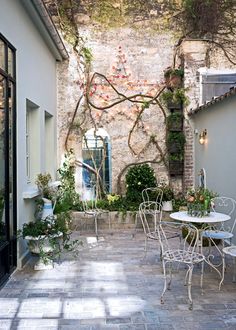 an outdoor patio with tables, chairs and potted plants on the side of it