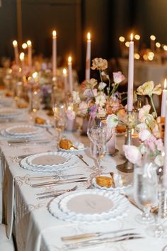 a long table is set with place settings and candles