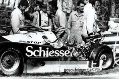 a group of men standing around a race car