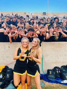 two girls in black and yellow cheer for the camera with their hands up as they stand next to each other