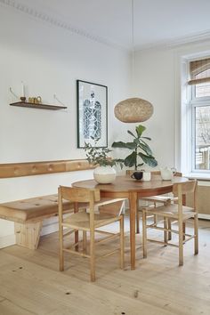 a dining room table and bench with potted plants