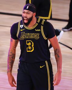 a man with a beard and tattoos on his face is standing in front of a basketball court