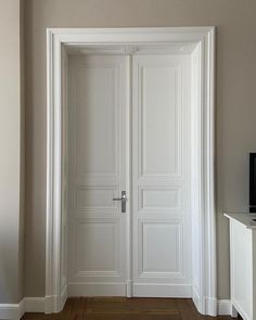 an empty room with two white doors and a tv on the wall in front of it