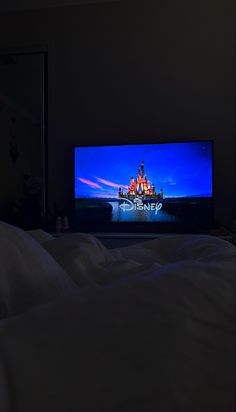 the television is turned on and it's glowing in the dark, with an image of disney castle