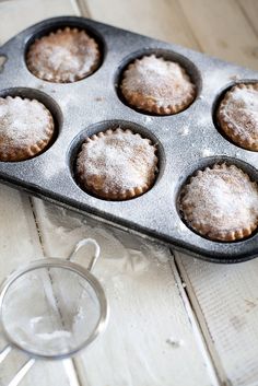 a muffin tin filled with cupcakes sitting on top of a wooden table