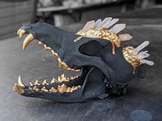 a black and gold animal skull with spikes on it's head is sitting on the ground