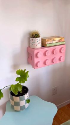 a potted plant sitting on top of a blue table next to a pink shelf