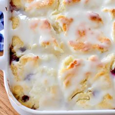 a casserole dish with cheese and blueberries in it on a wooden table