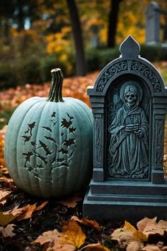 two pumpkins sitting on top of leaves in front of a grave with a statue