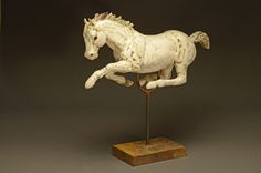 a statue of a white horse on top of a wooden stand in front of a black background