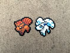 two pixelated stickers sitting next to each other on the ground in front of a wall