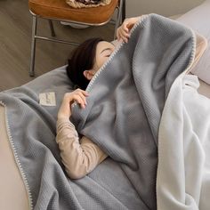 a woman laying on top of a bed under a blanket