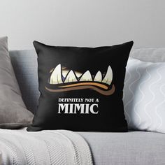 a black pillow with the words definitely not a mimic in front of it on a couch