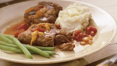 a white plate topped with meat, mashed potatoes and green beans