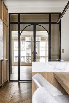 an open door leading into a room with wooden floors and white marble counter tops on either side