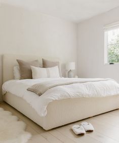 a bedroom with white walls and flooring has a large bed in the middle, along with two pillows on the side