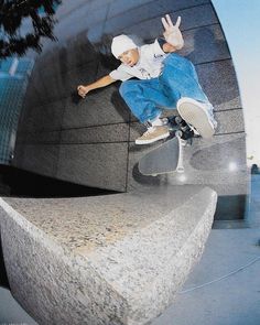 a man riding a skateboard up the side of a cement wall with his hands in the air