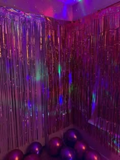 some purple balls are sitting in front of a curtain with lights on it and curtains hanging from the ceiling