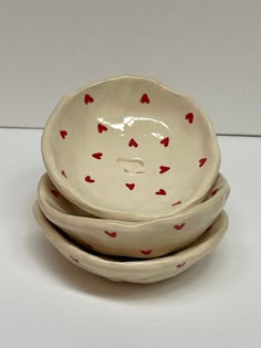 three bowls with red hearts on them are stacked in the shape of an elephant's head