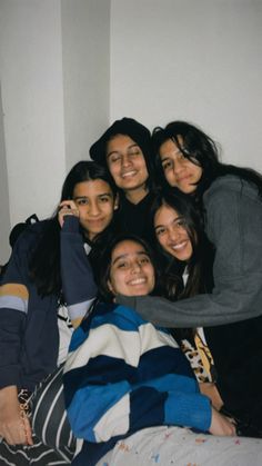 a group of young women are posing for a photo together on the bed with their arms around each other