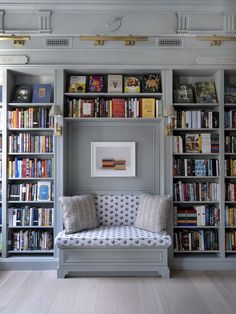 a living room filled with lots of books on top of a book shelf next to a couch