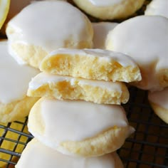 lemon cookies with white icing stacked on top of each other in front of sliced lemons