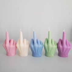 five candles in the shape of hands with one lit candle on each hand, all different colors