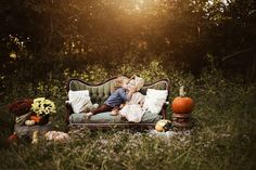 two children are sitting on an old couch in the middle of a field with pumpkins