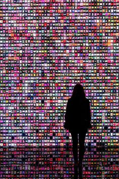 a person standing in front of a wall covered with lots of different colored squares