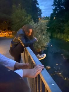 a man riding a skateboard on top of a metal rail next to a river