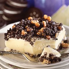 a piece of ice cream cake on a plate with a fork and cookies in the background