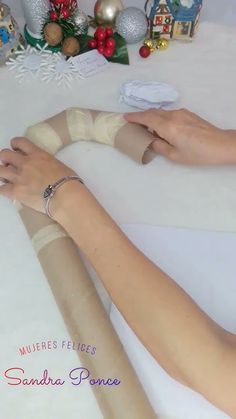 two hands on a white table with christmas decorations and ornaments in the backgroung