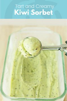 a spoon full of guacamole sitting on top of a glass container filled with green liquid