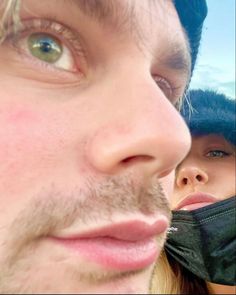 a close up of a person with a hat on and another man in the background