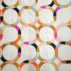 a white quilt with circles on it and pink, black, yellow, orange, and grey colors