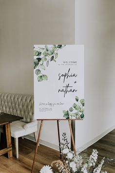 a welcome sign sitting on top of a wooden easel in front of a couch