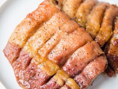 two pieces of meat sitting on top of a white plate covered in powdered sugar