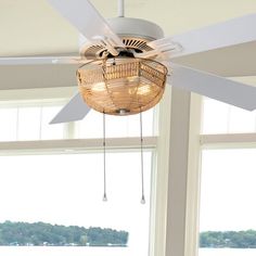 the ceiling fan is hanging from the ceiling in front of two large windows overlooking water