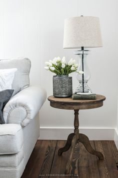 a living room with a couch, chair and lamp on the side table in front of it