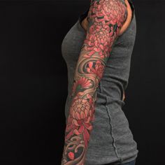 a woman's arm covered in tattoos with red flowers on the top and bottom